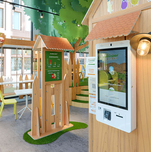 Salle de fast food avec borne de commande.